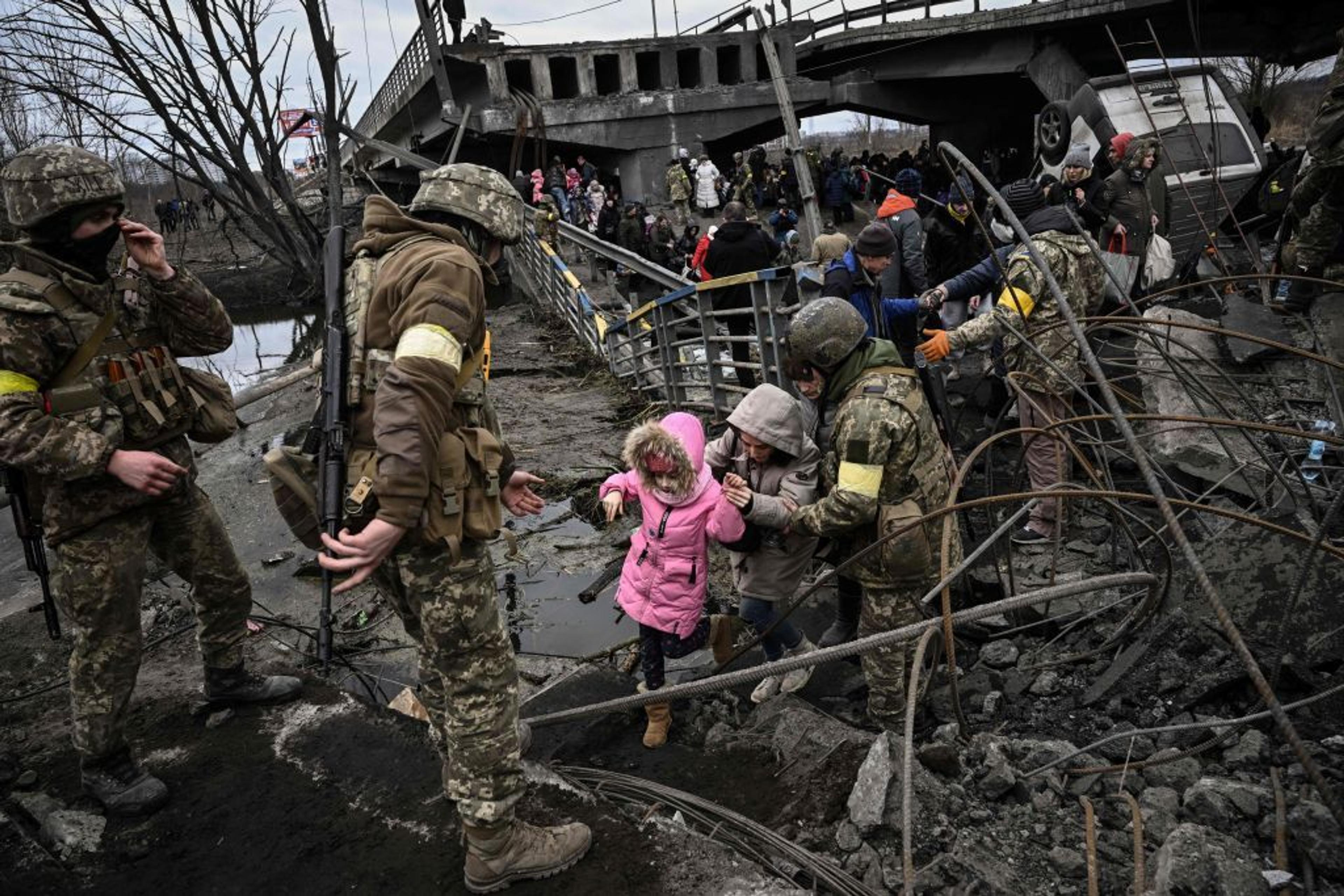 People cross a destroyed bridge as they evacuate the city of Irpin, northwest of Kyiv, during heavy shelling and bombing, 10 days after Russia launched a full-scale invasion of Ukraine, on March 5, 2022.
