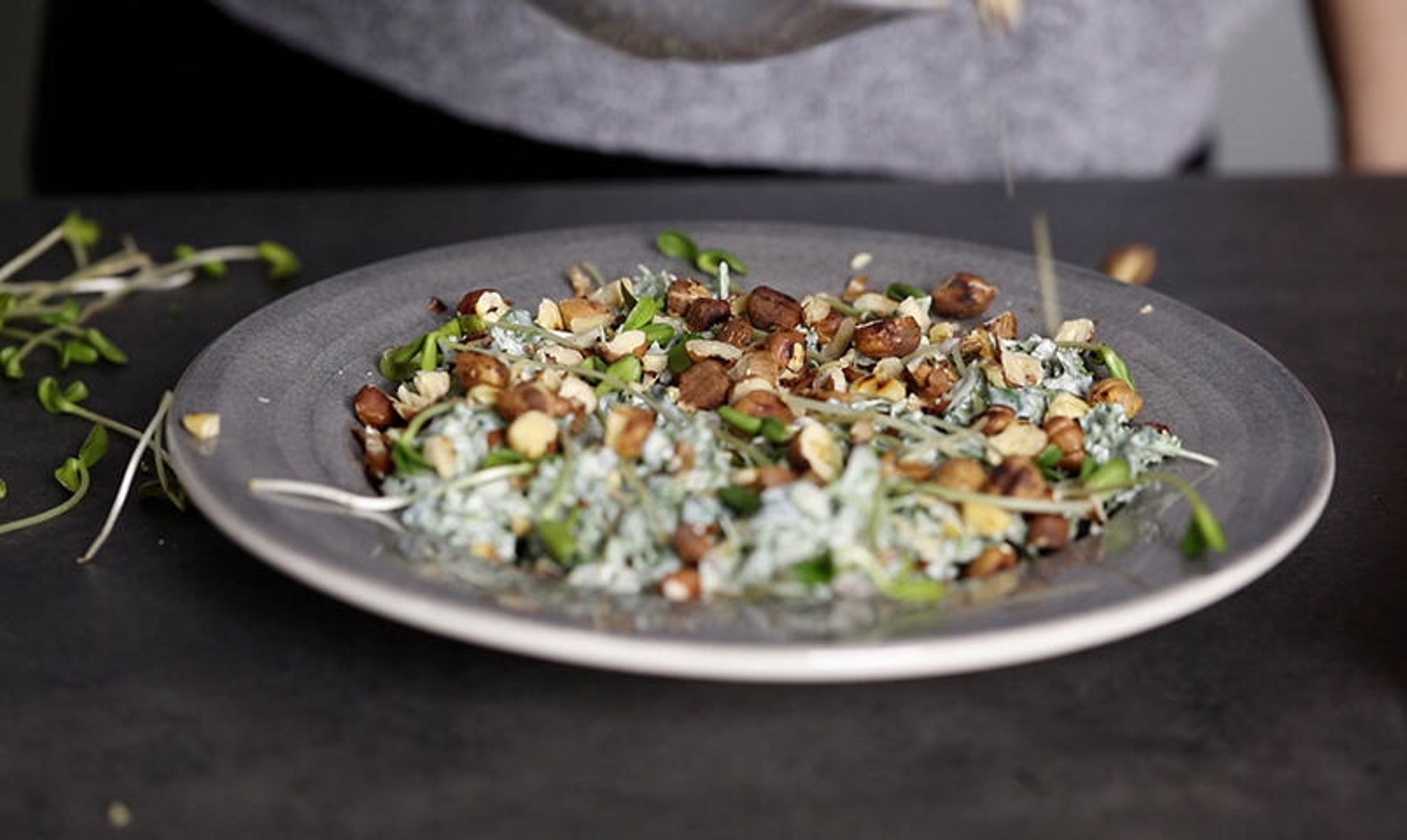Keramikfat med grönkålsskott, matyoghurt och hackade hasselnötter.