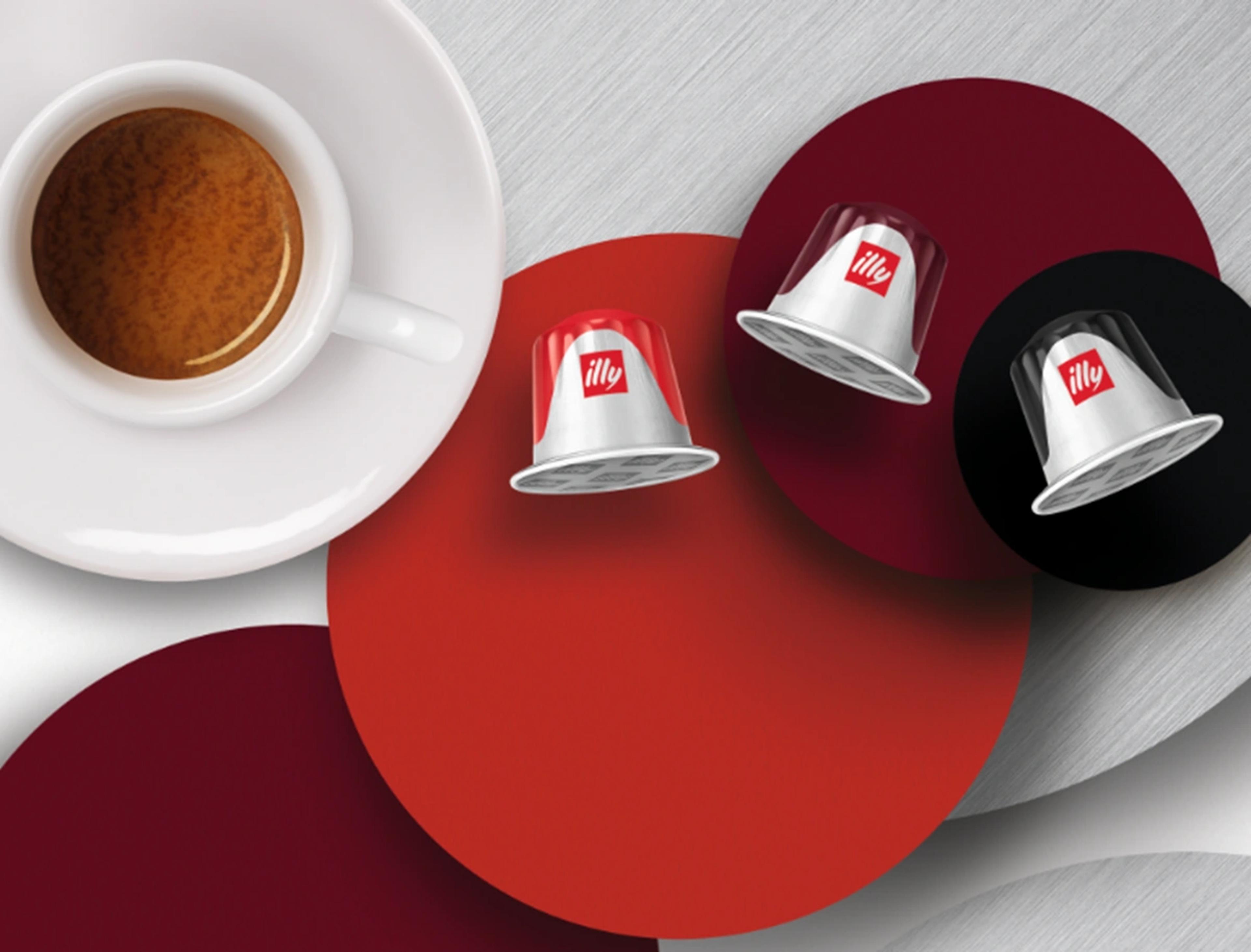 Three illy coffee capsules on red, burgundy and black circles next to a cup of espresso on a saucer.