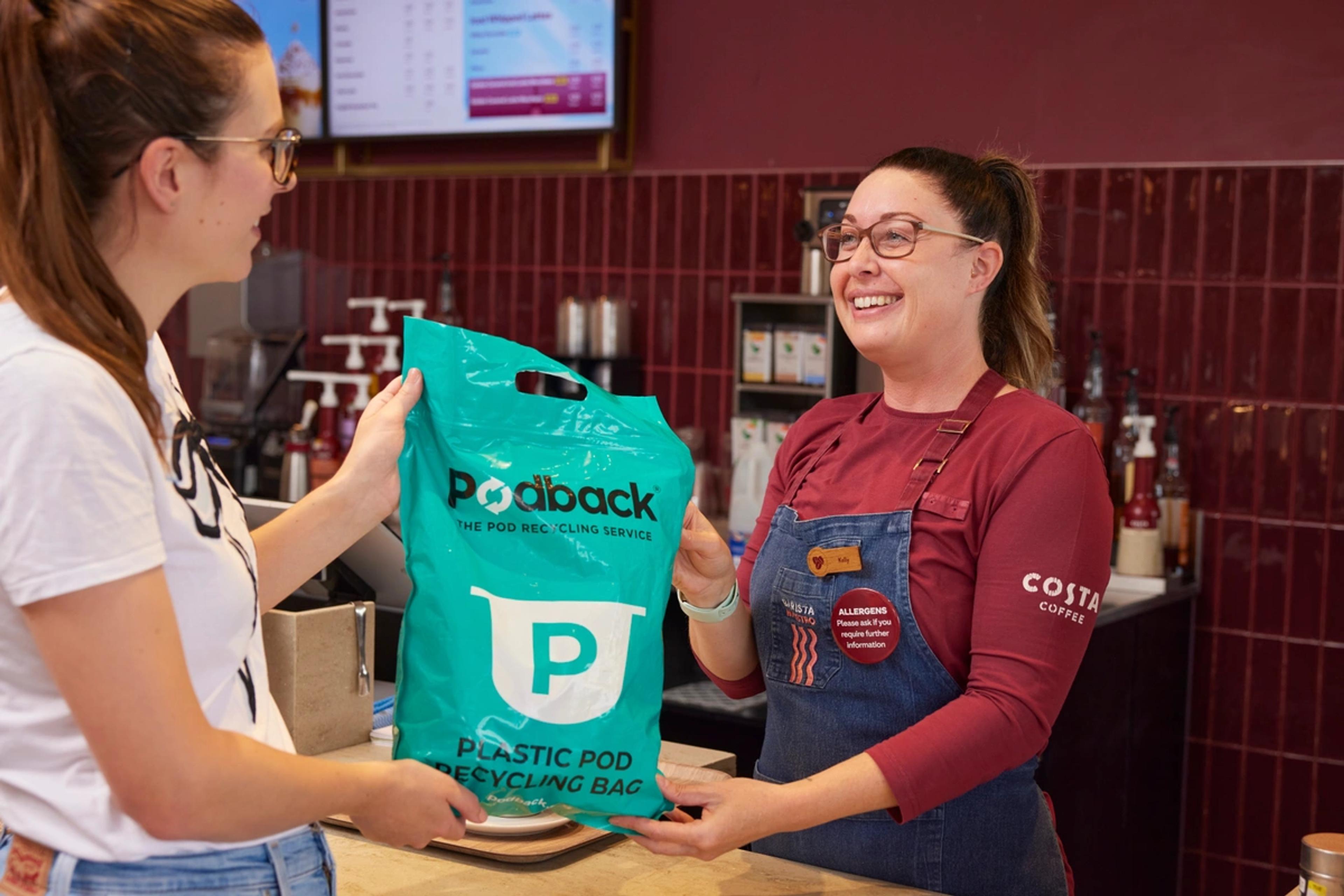 coffee shop customer handing a green Podback recycling bag to a Costa Coffee barista