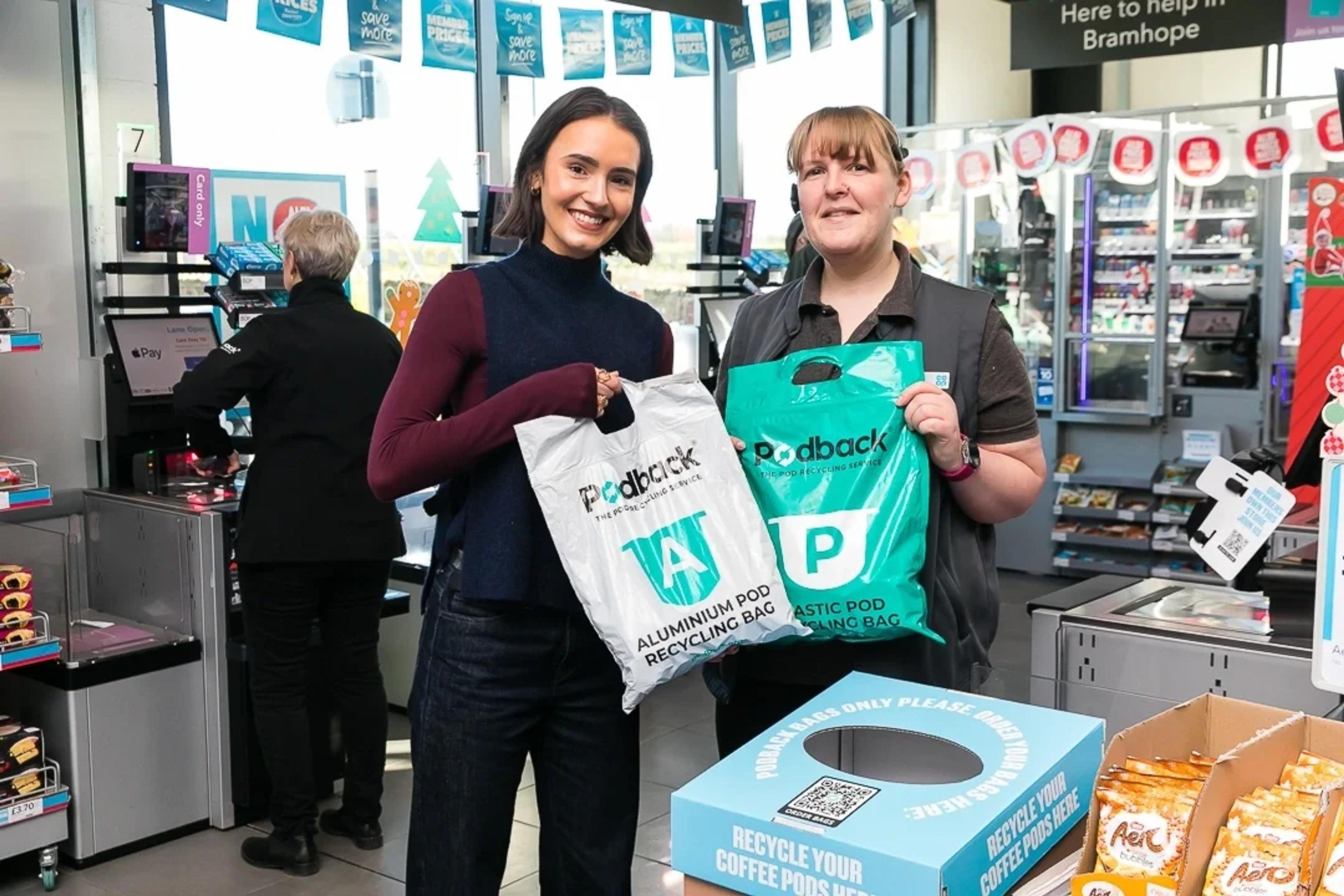 A customer and member of Co-op staff with green and white Podback recycling bags