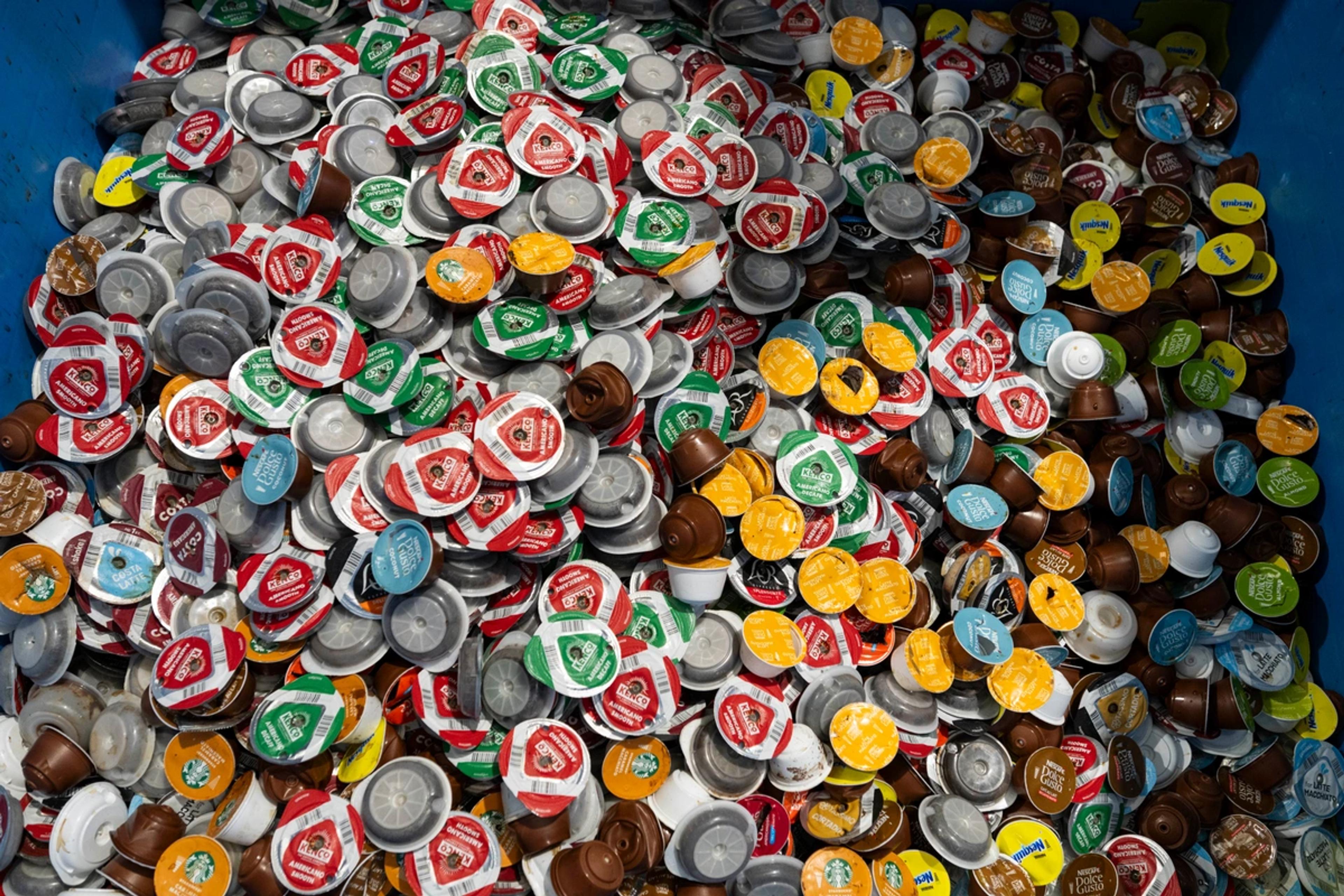 A container filled with hundreds of used coffee pods from many different brands, collected for recycling.