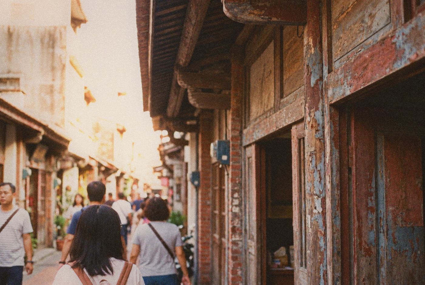 Pedestrians beside weathered brick and timber shopfronts
