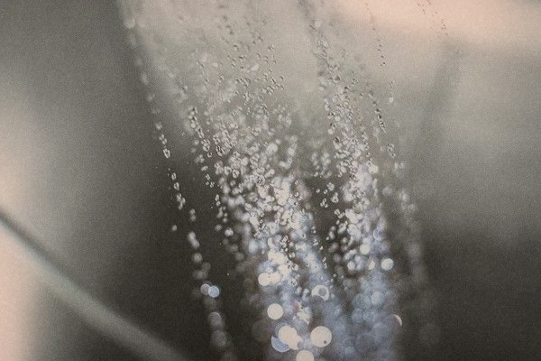 Close-up of water droplets spraying from an out-of-focus shower head