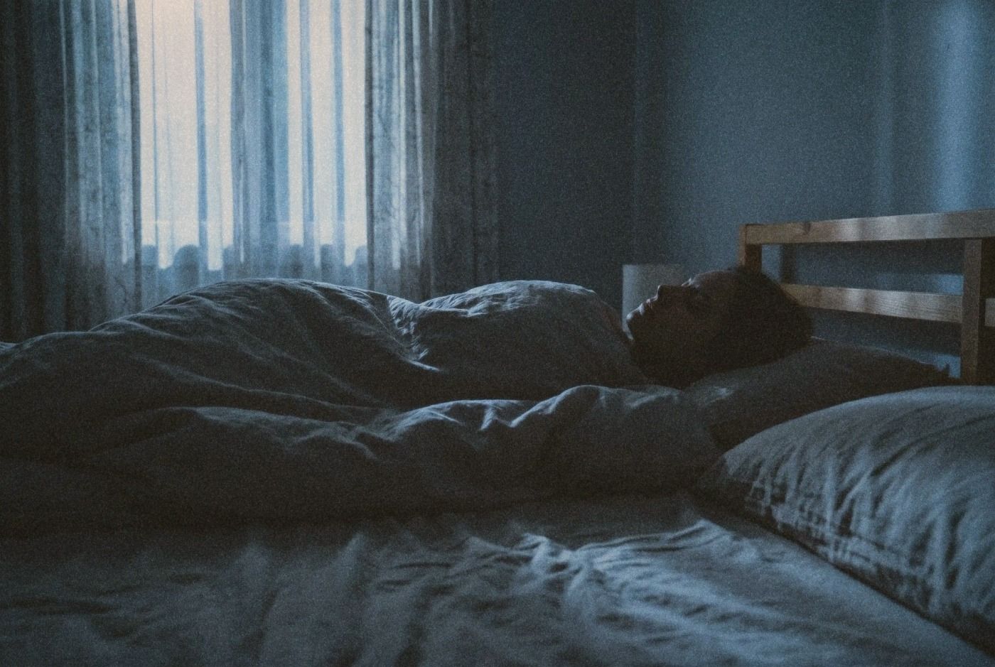 Person lying in bed in a dark room