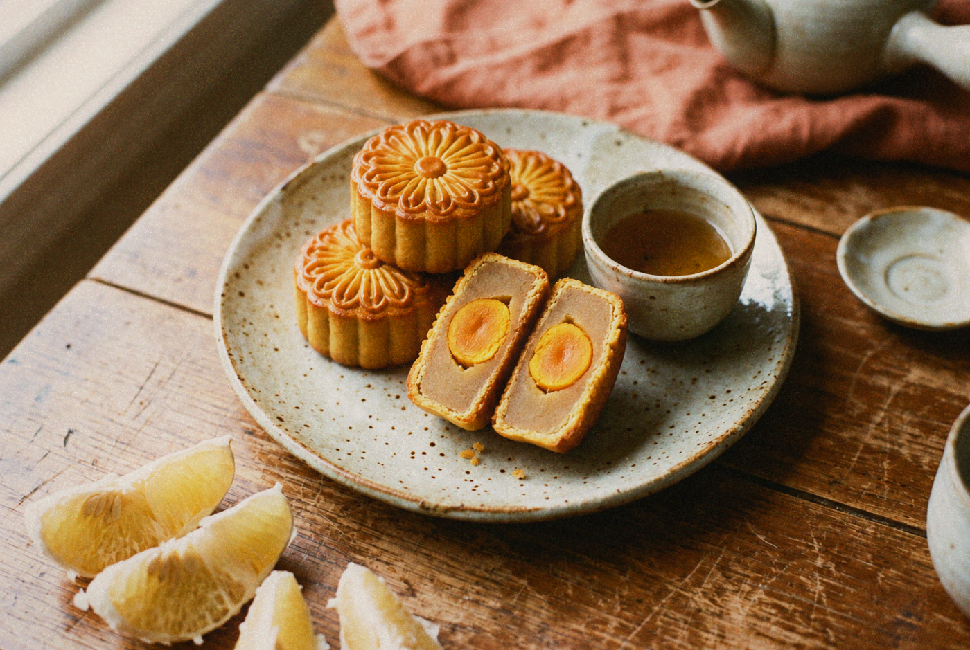 Overhead close-up of a Taiwanese mooncake cut in half showing a golden salted egg yolk, tea beside it