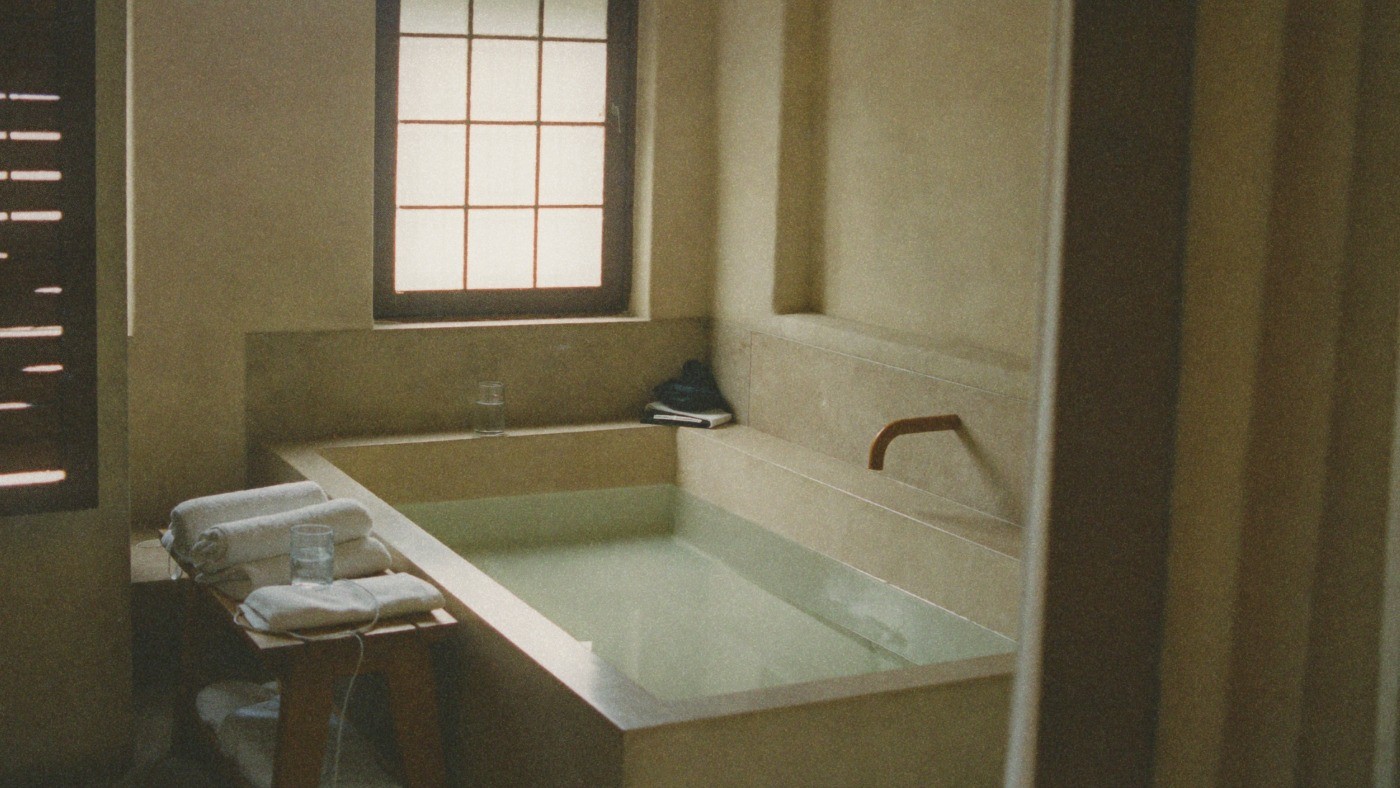 Analogue-style generated illustration of an empty private bath, with folded cotton towels and a glass of water.