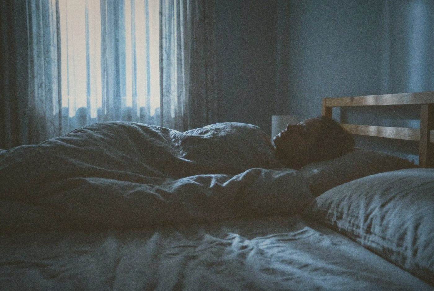 Person lying in bed in a dark room
