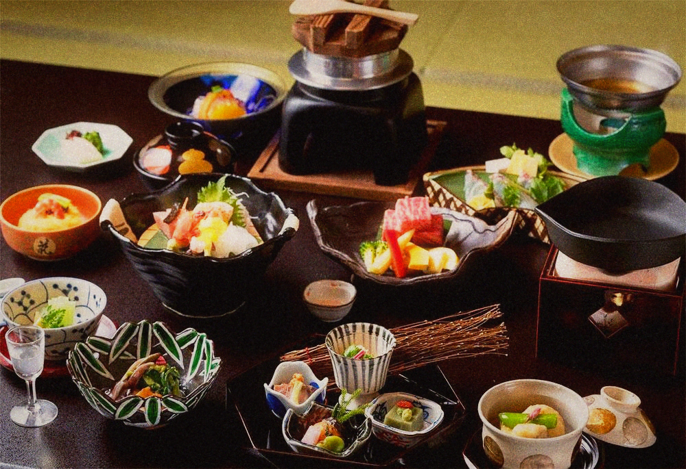 Multi-course kaiseki meal in many small bowls with sashimi, a tabletop burner and sake
