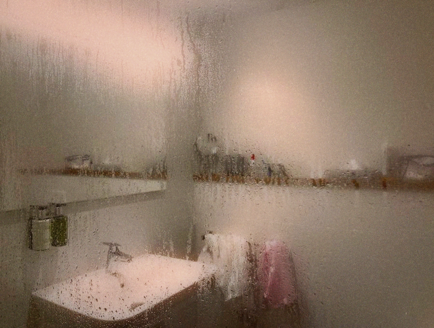 A small Taipei apartment bathroom with condensation on the mirror and toiletries crowded on limited surfaces