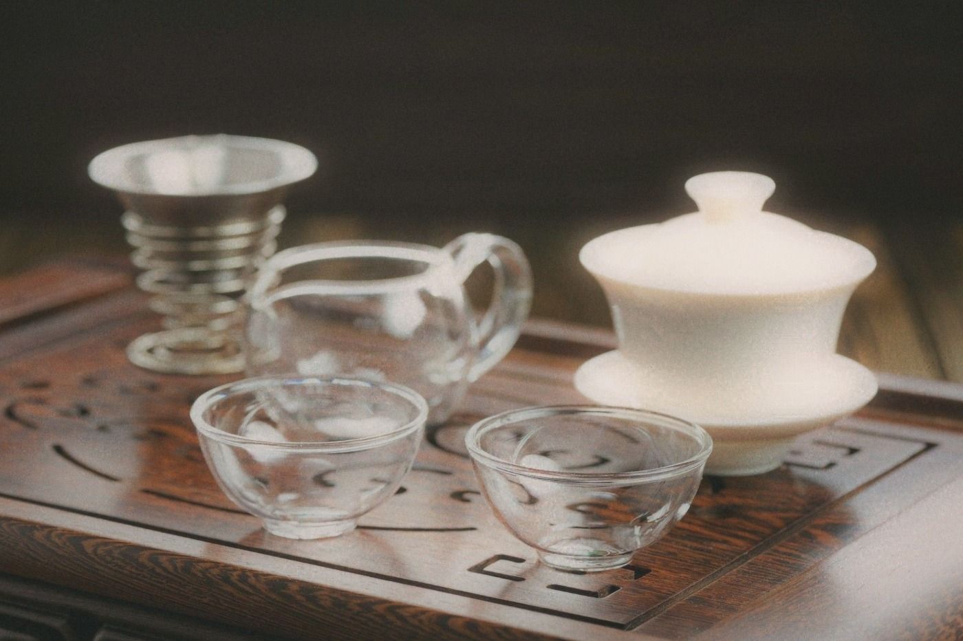 Close-up of ceramic tea cups and a gaiwan on a simple tray