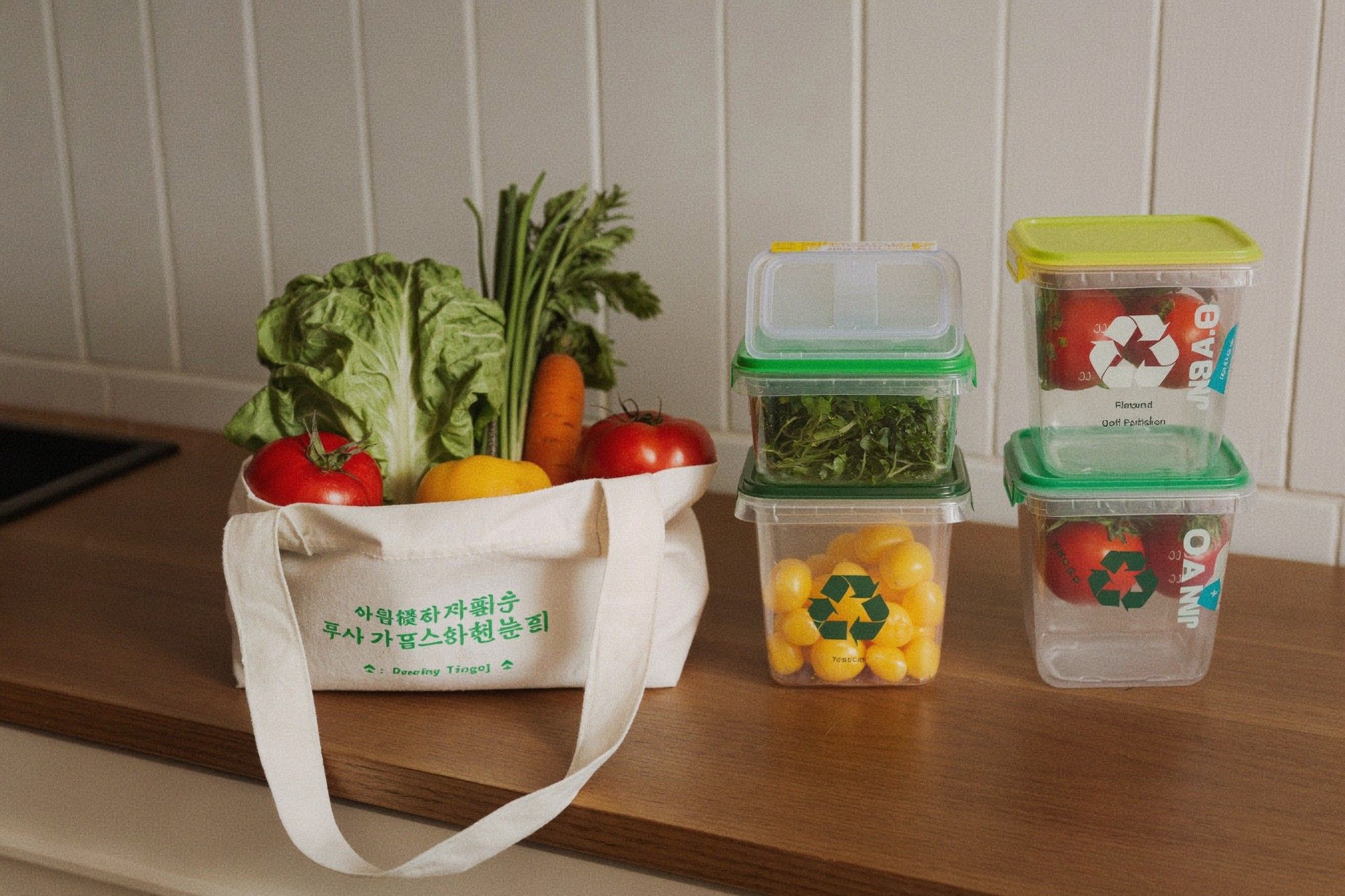 Reusable shopping bag and food containers filled with fresh market vegetables on a kitchen counter