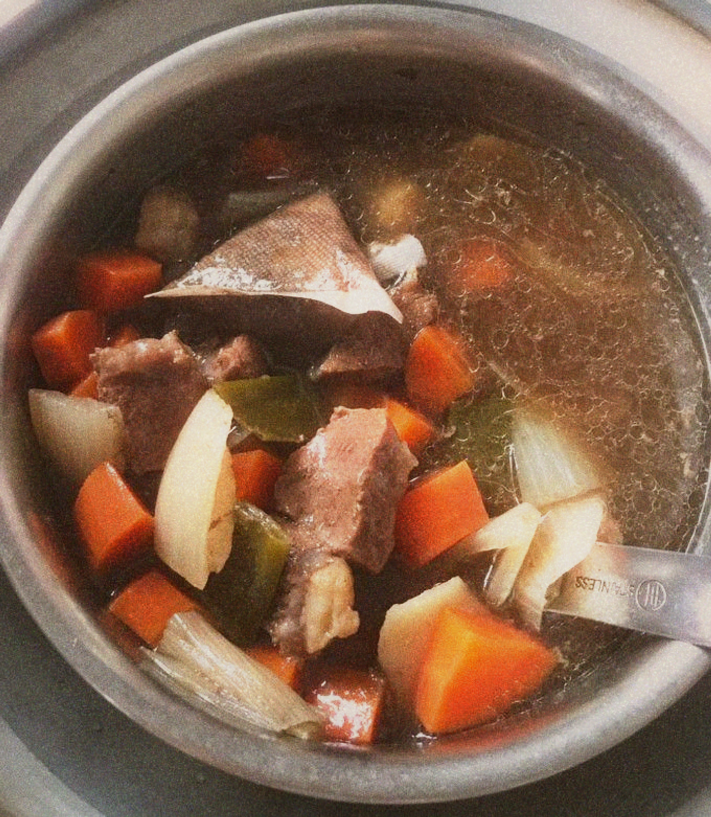 A bubbling pot of red-braised beef broth with star anise and scallions visible