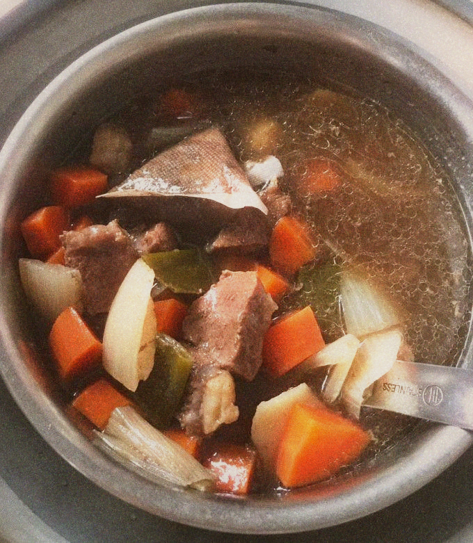 A bubbling pot of red-braised beef broth with star anise and scallions visible