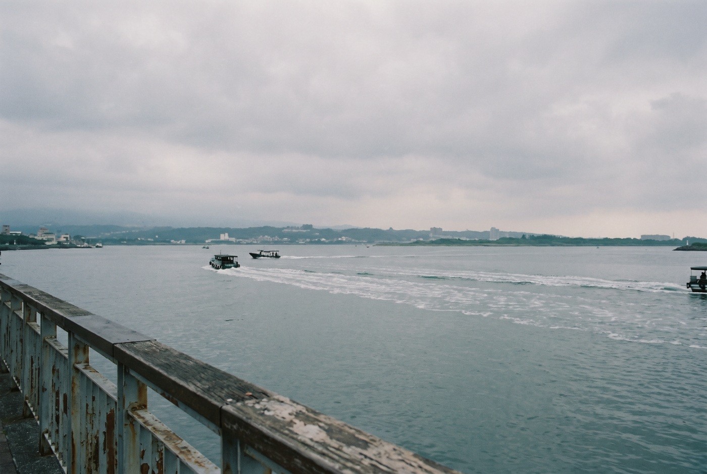Illustration: Ferries crossing the water beyond a weathered railing.