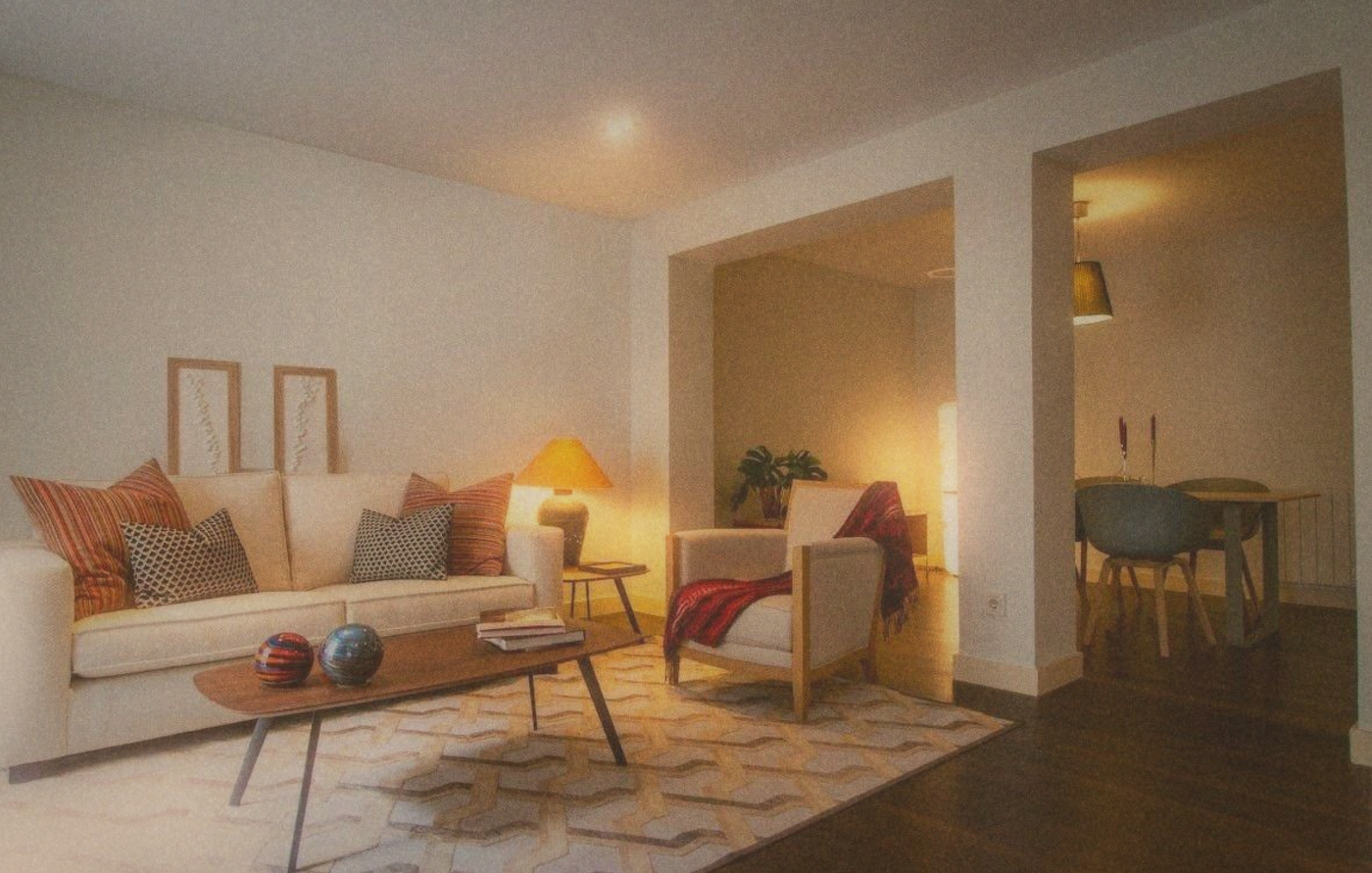 A soft-lit living room at 9pm, one warm lamp on, a cup of tea on the table, no screens visible