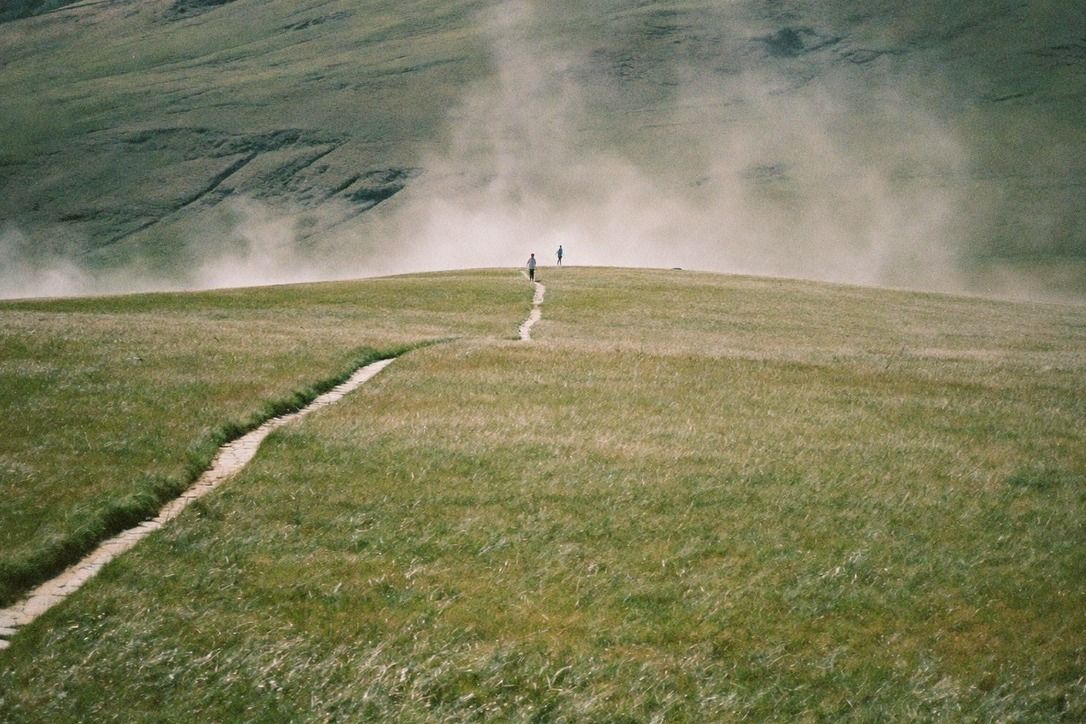 Open windswept grassland plateau on a mountain above Taipei with mist drifting over the grass and hikers on a stone path