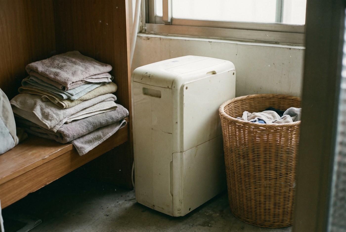 Illustration: a dehumidifier beside a laundry basket.