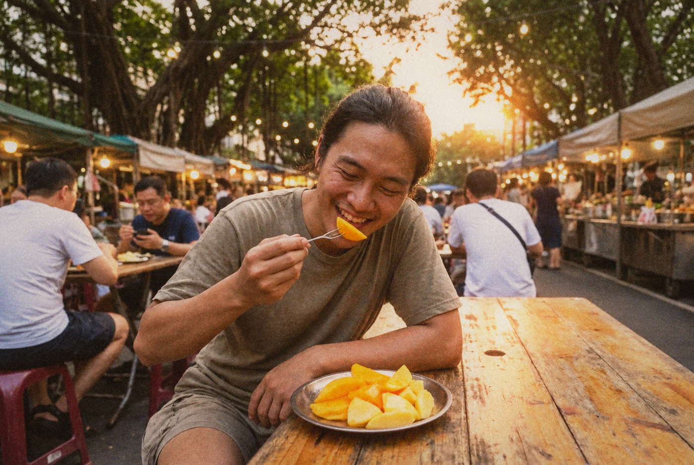 Person eating fresh mango with a small fork at an outdoor table