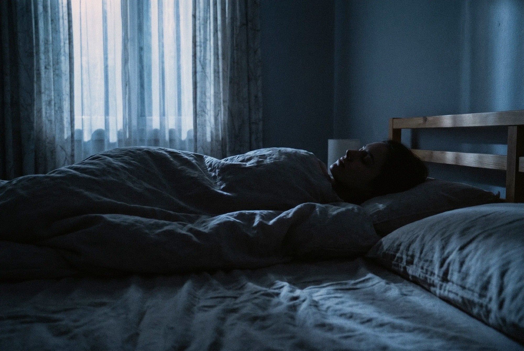 Person lying in bed in a dark room