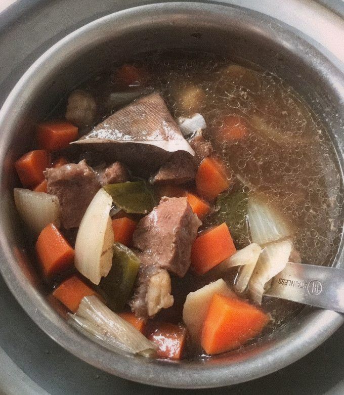 A bubbling pot of red-braised beef broth with star anise and scallions visible