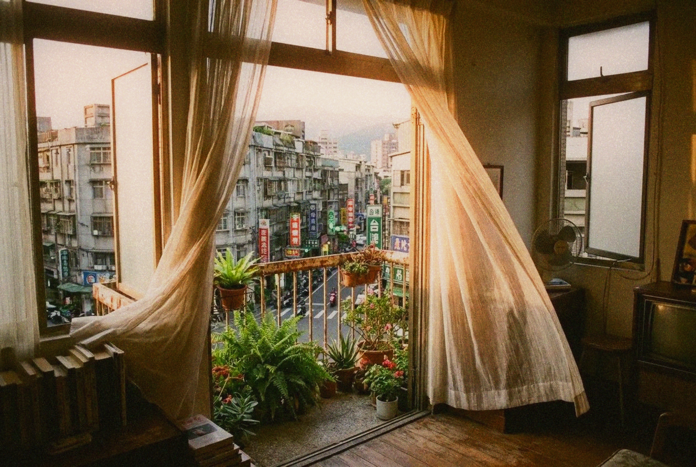 View from inside a Taipei apartment looking out through an open window with sheer curtains catching a breeze