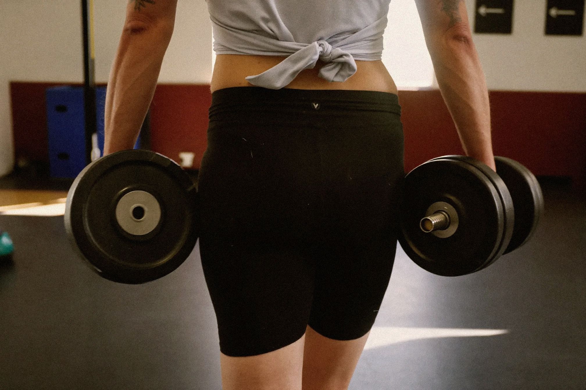 Person carrying heavy dumbbells for farmer's walks in a gym