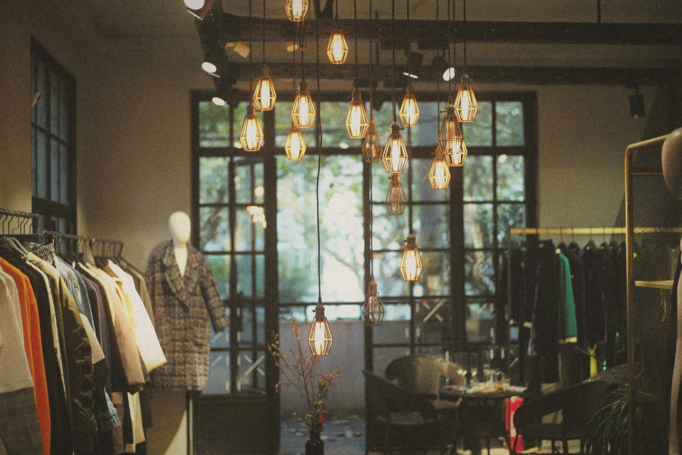 Clothing boutique interior with caged pendant bulbs, garment rails and a mannequin in a tweed coat