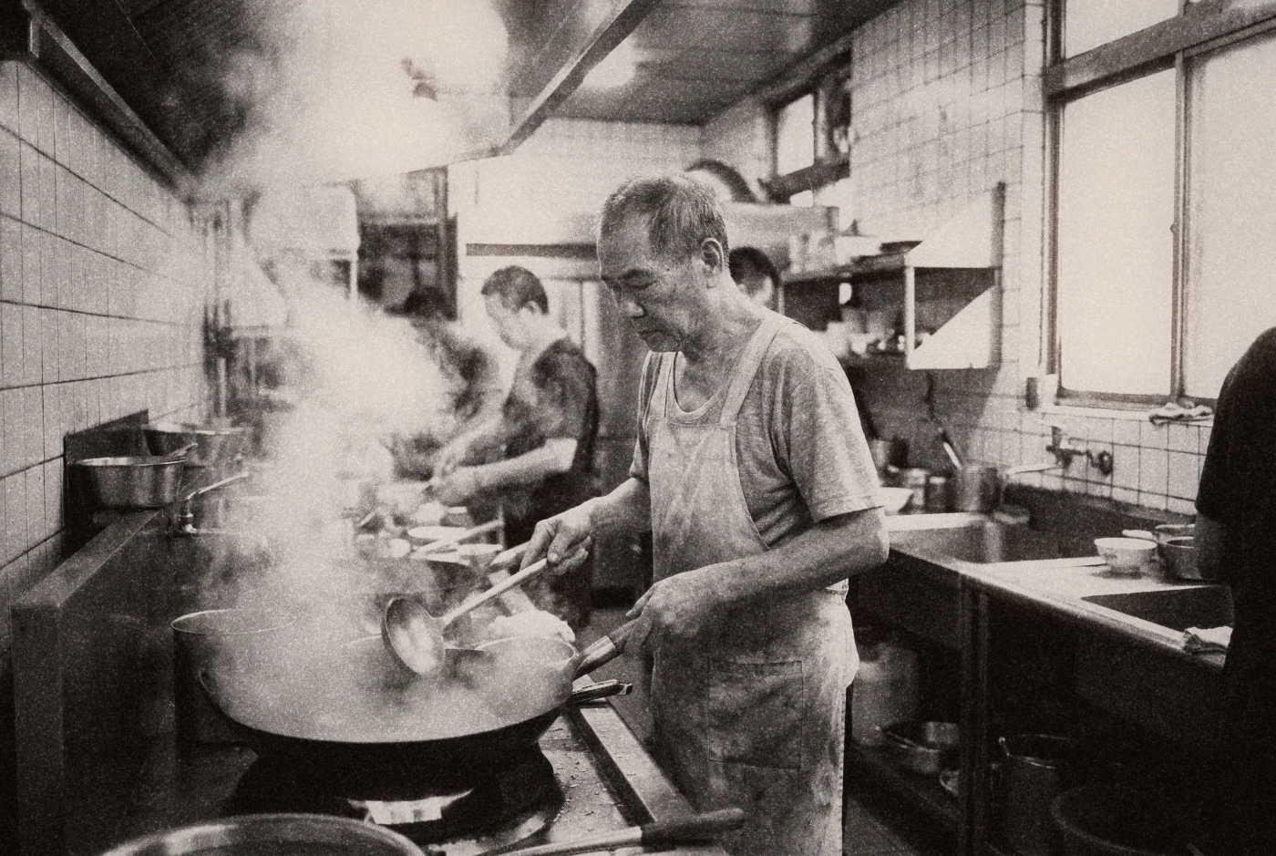 Elderly Taiwanese cook at a wok station in a traditional restaurant kitchen