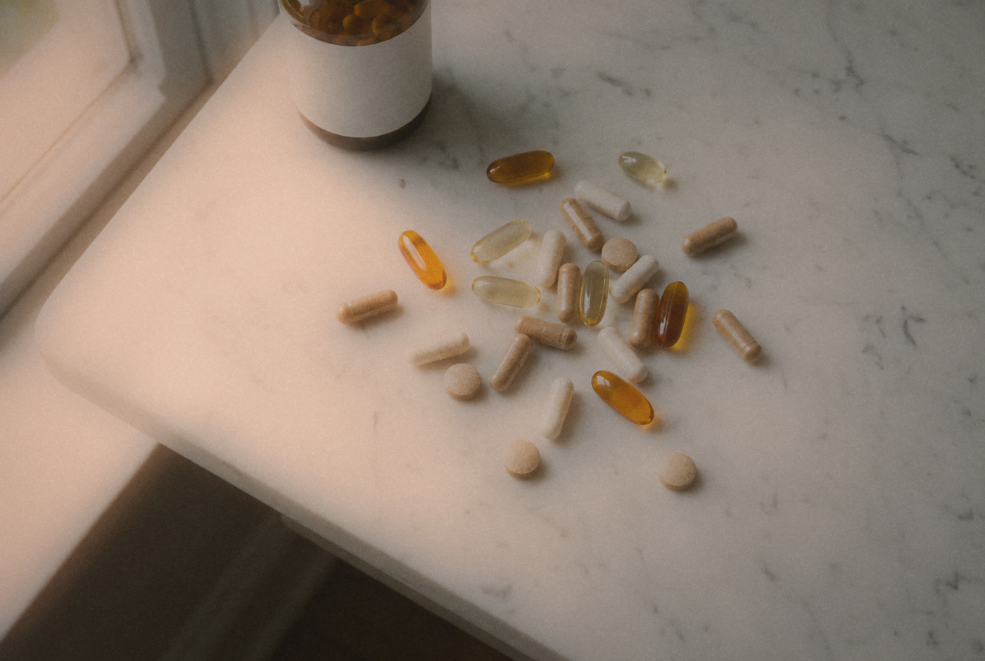 Capsules and tablets scattered beside an amber bottle