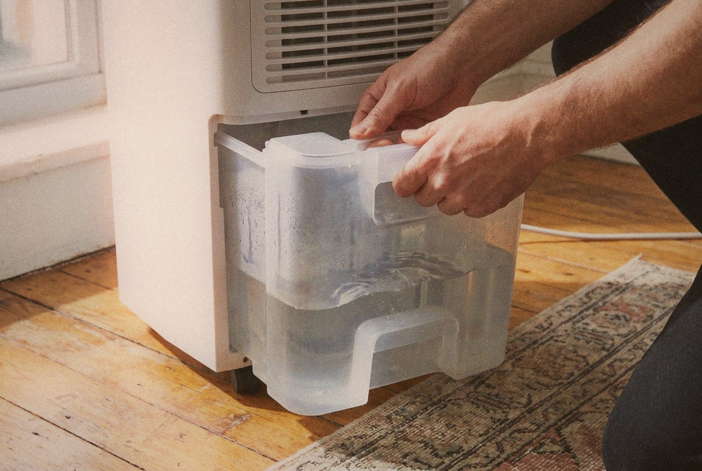 Illustration: removing a dehumidifier water tank.