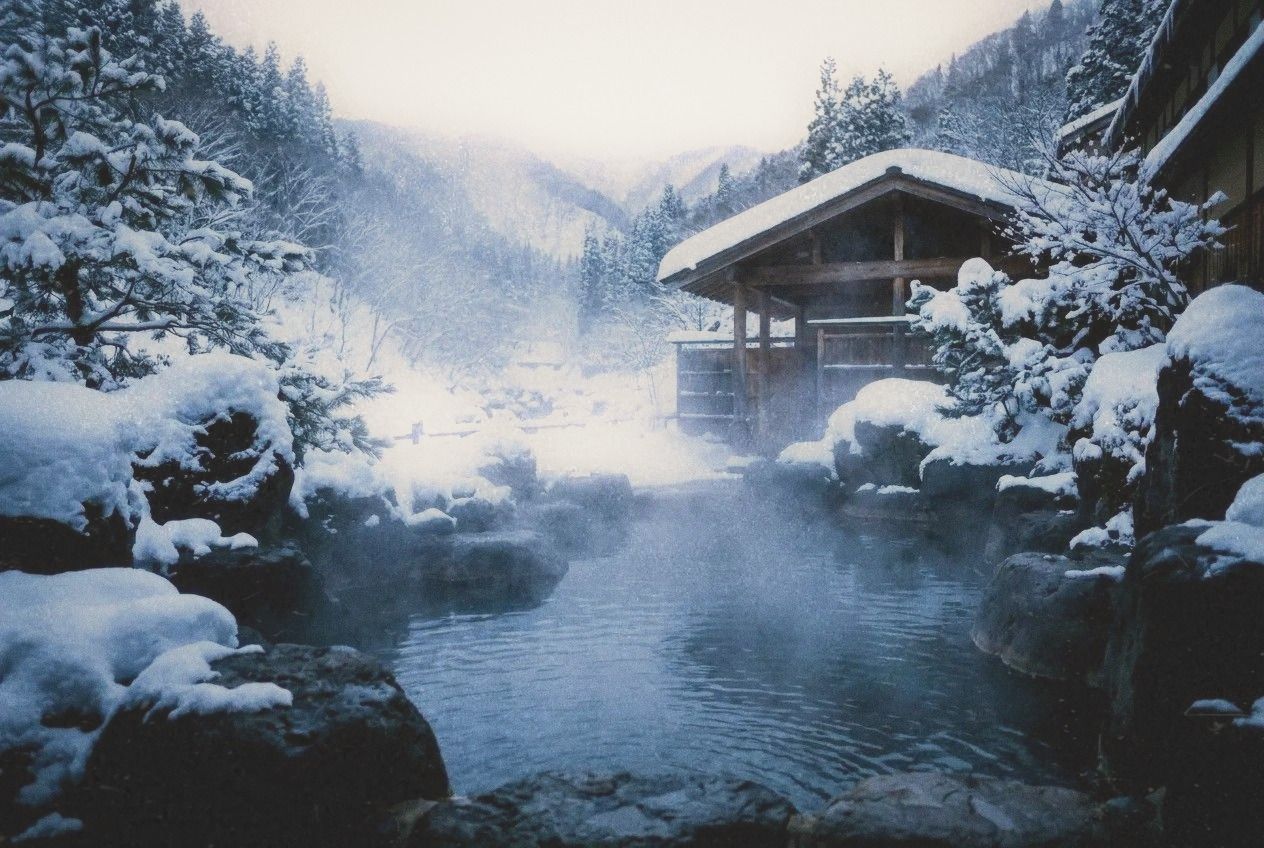 Snow-covered outdoor onsen bath at a mountain ryokan