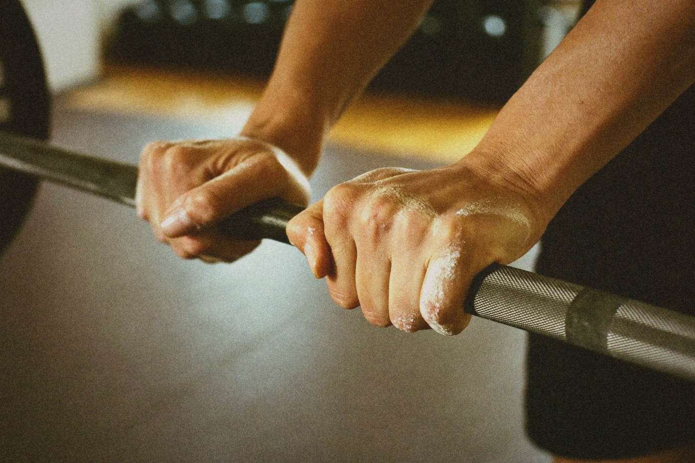 Close-up of chalked hands gripping a barbell in a gym