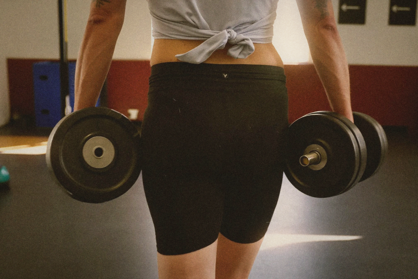 Person carrying heavy dumbbells for farmer's walks in a gym