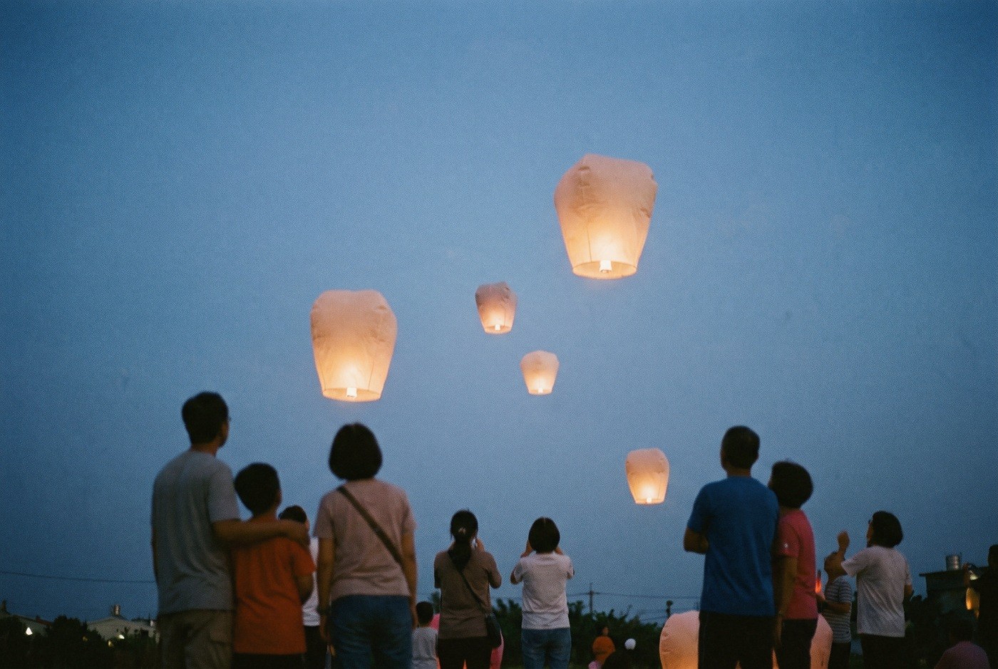 Illustration: A small gathering watching paper lanterns rise.