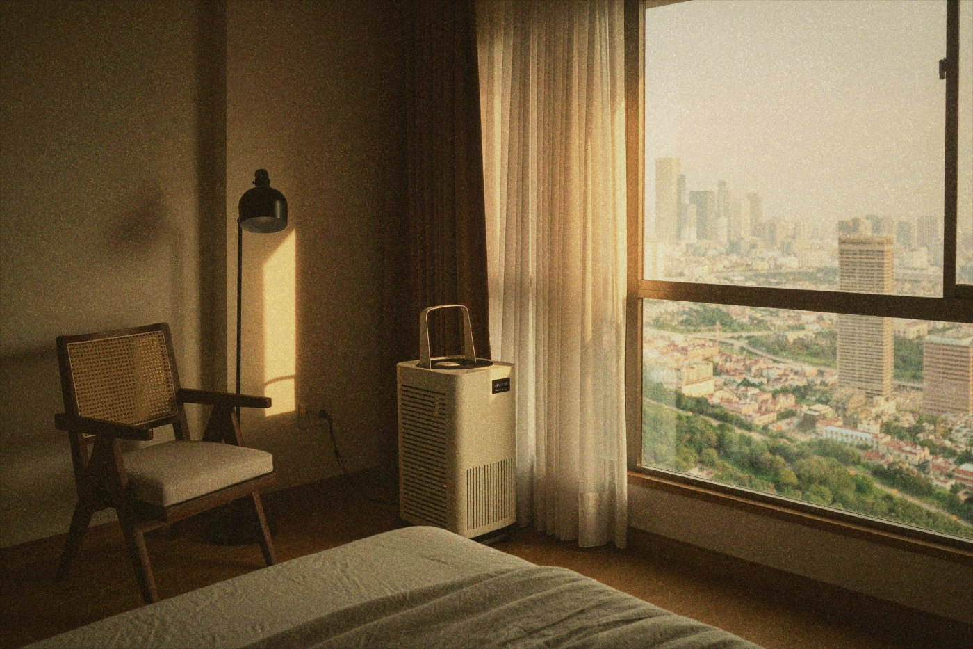 Air purifier next to a window with curtains and a chair in a bright Taipei apartment