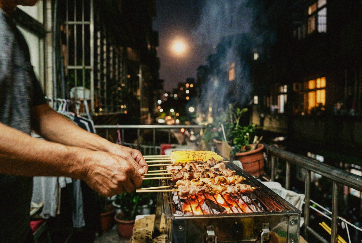 Hands turning skewers and corn over a small charcoal grill at night with a full moon behind