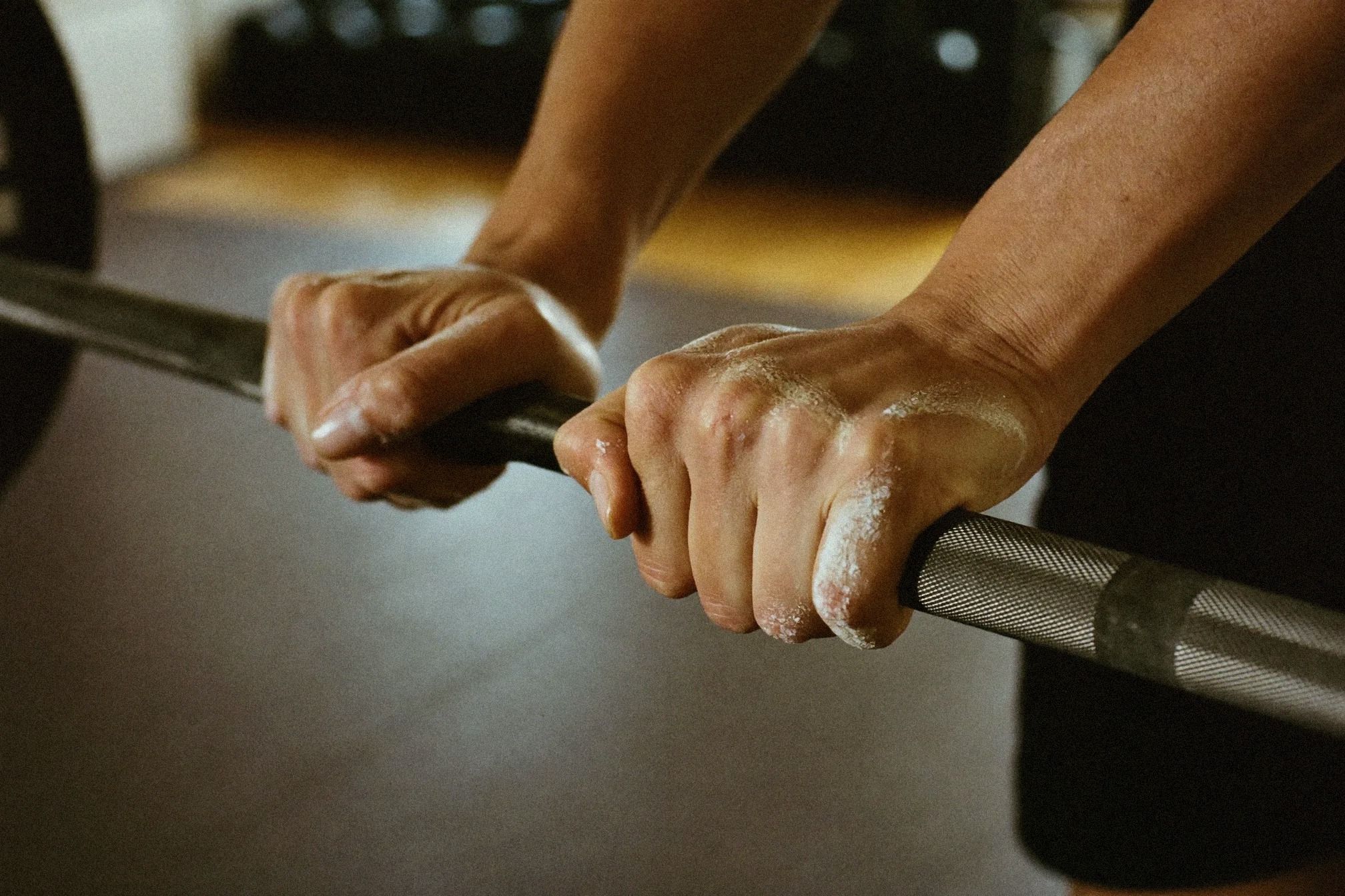 Close-up of chalked hands gripping a barbell in a gym