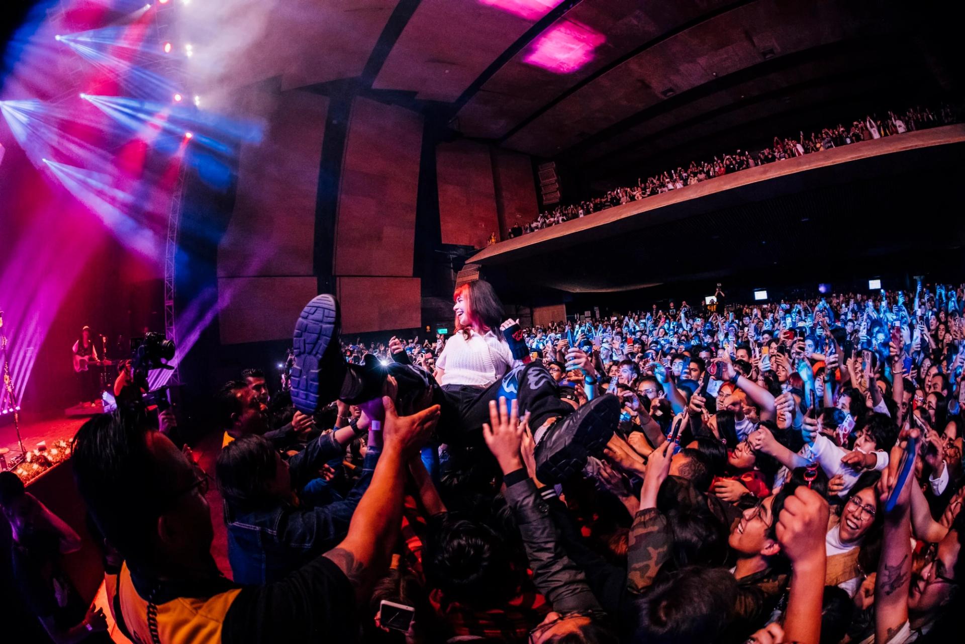 Foto energética de la artista Bratty haciendo crowd surfing en su concierto en vivo