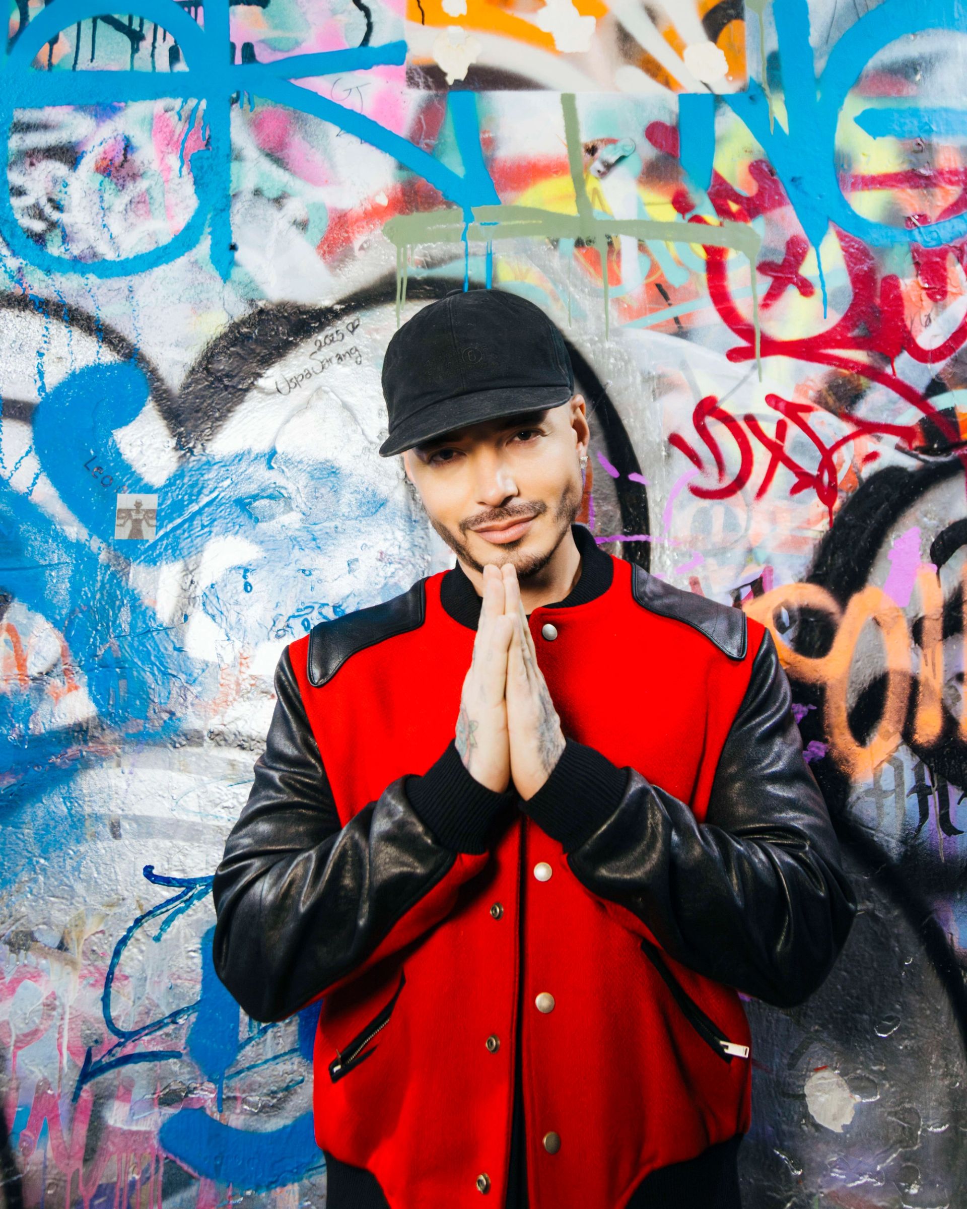 Retrato de J Balvin usando una gorra negra y chamarra roja en Ciudad de México, fotografía por Alan Cortés
