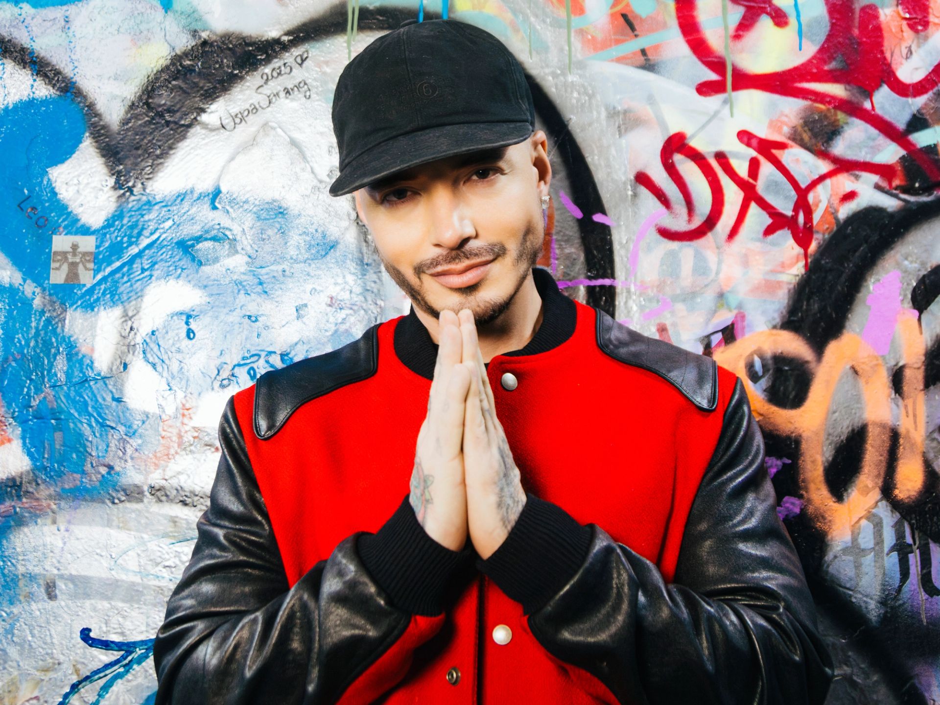 Retrato de J Balvin en Ciudad de México con chaqueta roja y gorra negra, mirando a la cámara. - Fotografía por Alan Cortés
