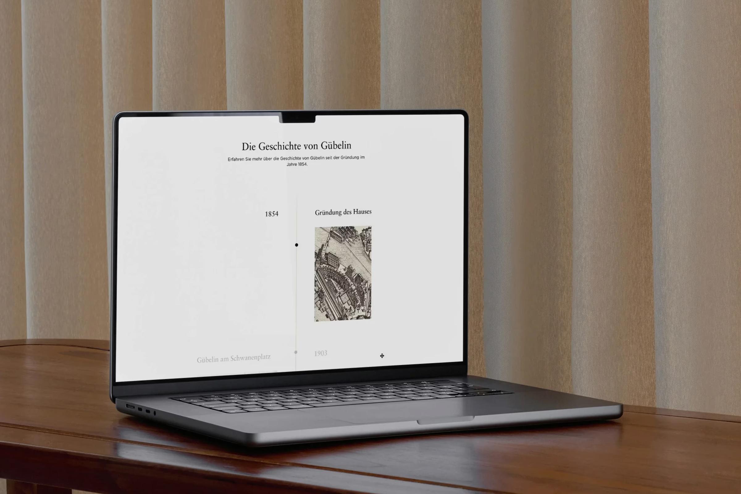 Laptop mit der Seite «Die Geschichte von Gübelin» auf einem Holztisch