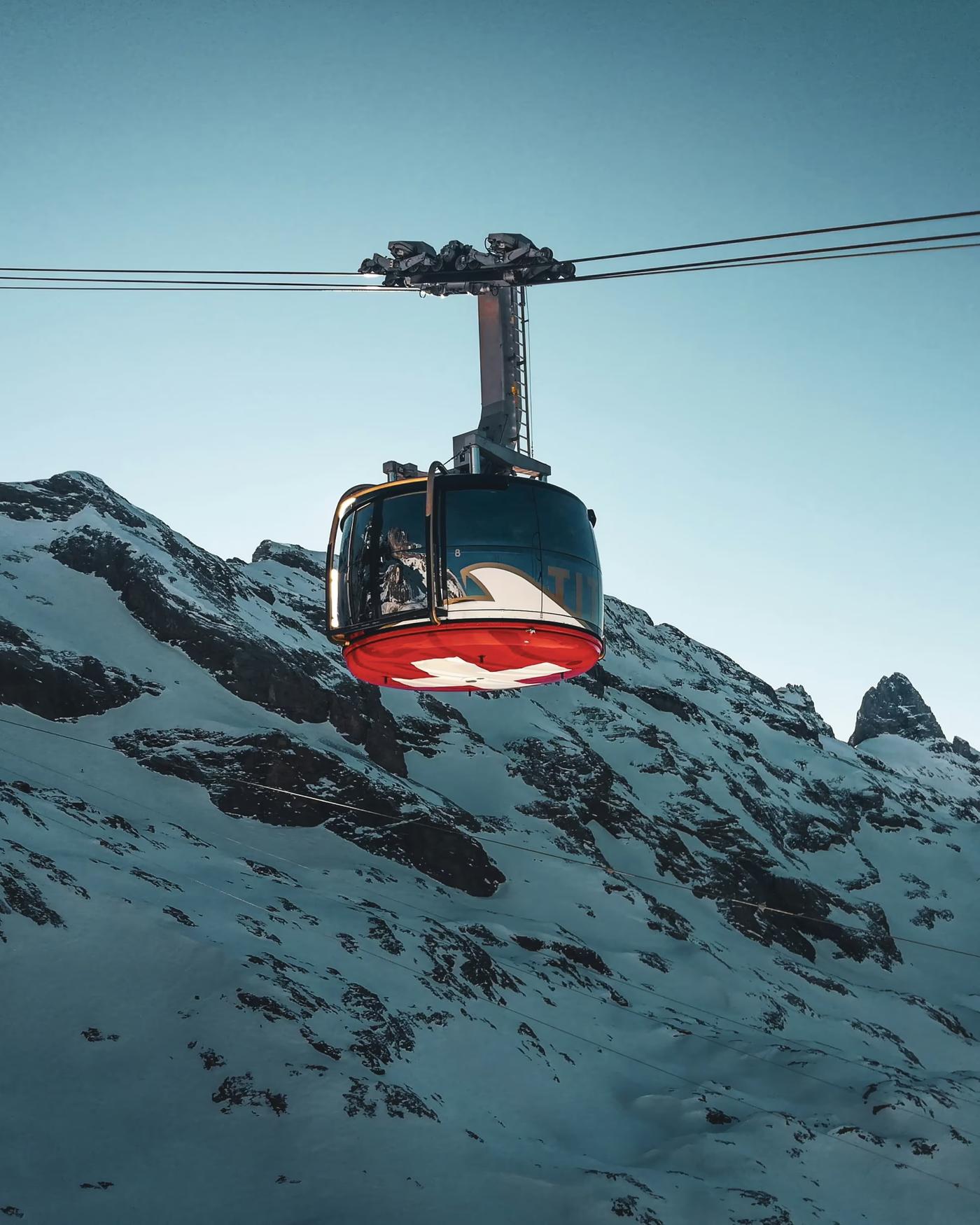 Seilbahnkabine mit Schweizer Kreuz vor verschneiten Felsen