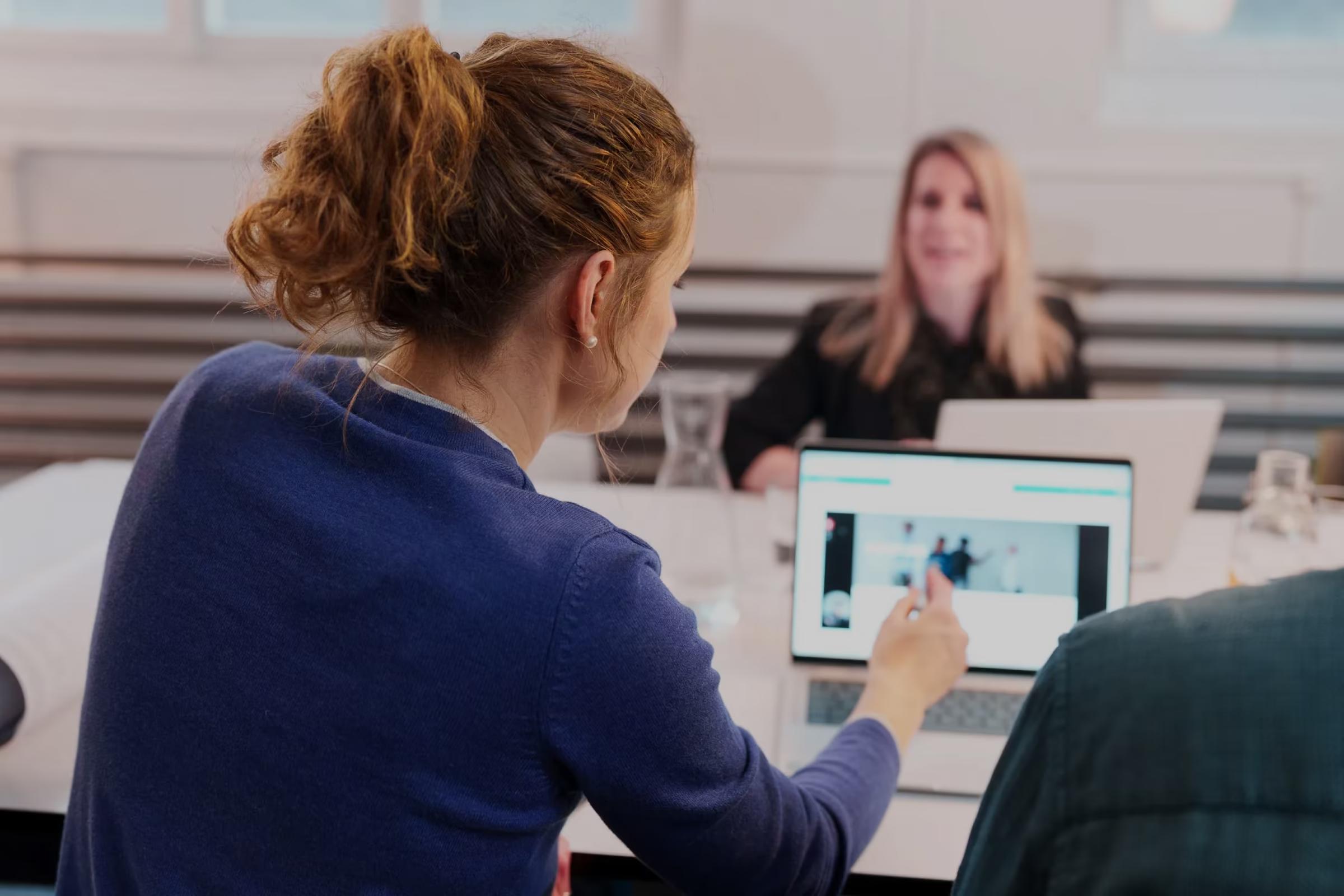 Zwei Frauen in einer Besprechung bei Rexult, eine zeigt auf einen Laptop