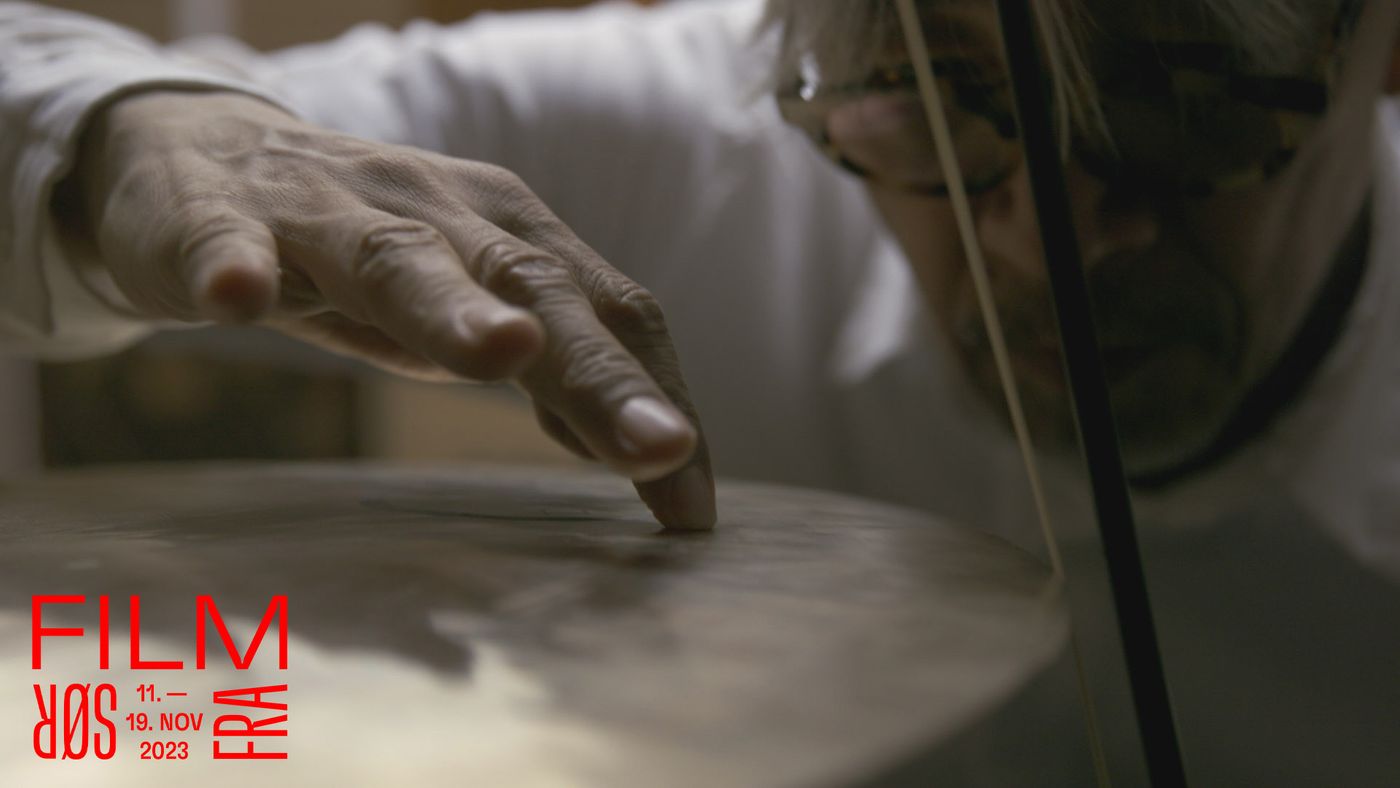 En mann stryker en bue på en cymbal