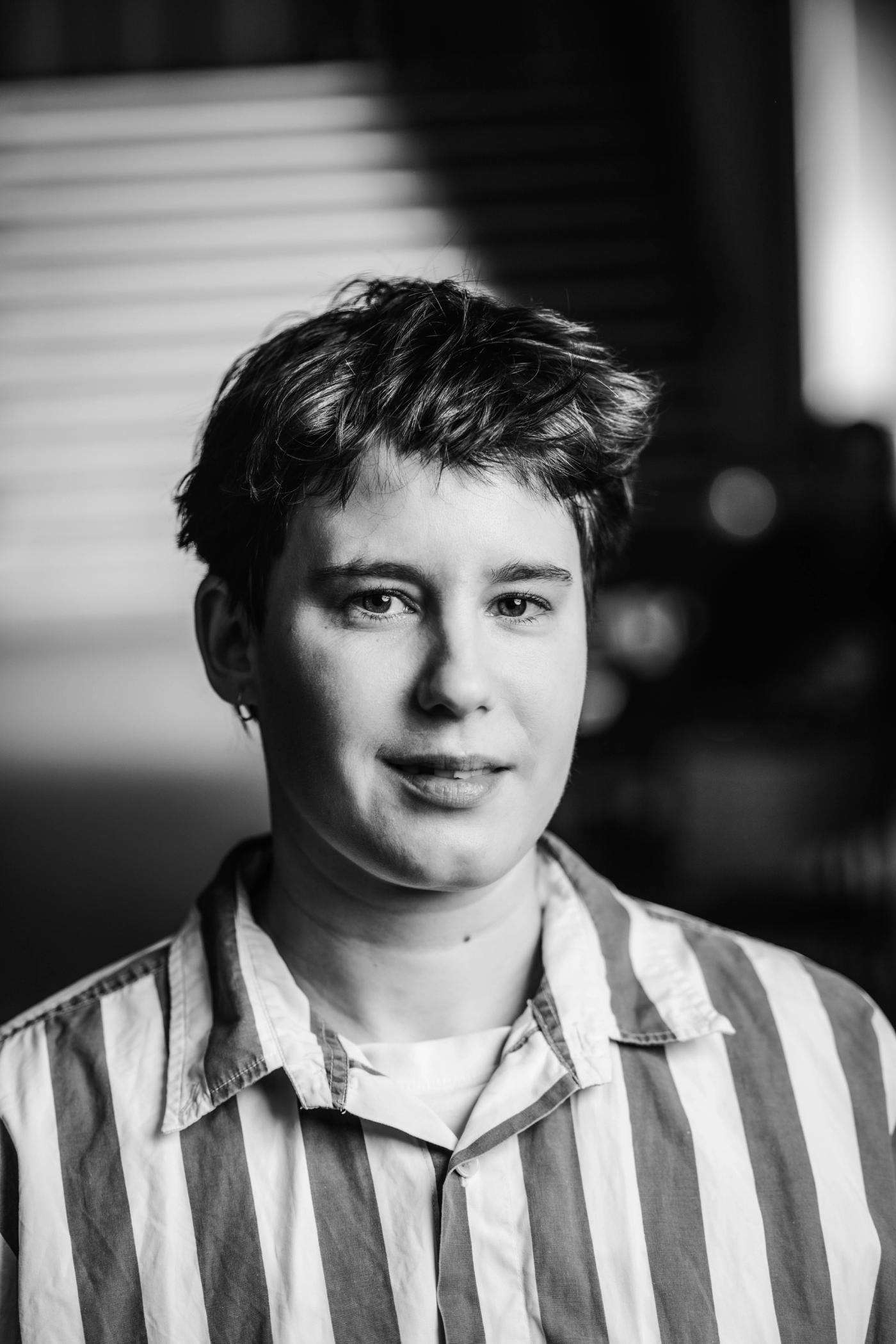 Koselig jente med mørkt kort hår og stripete skjorte. Snille øyne og et godt smil.