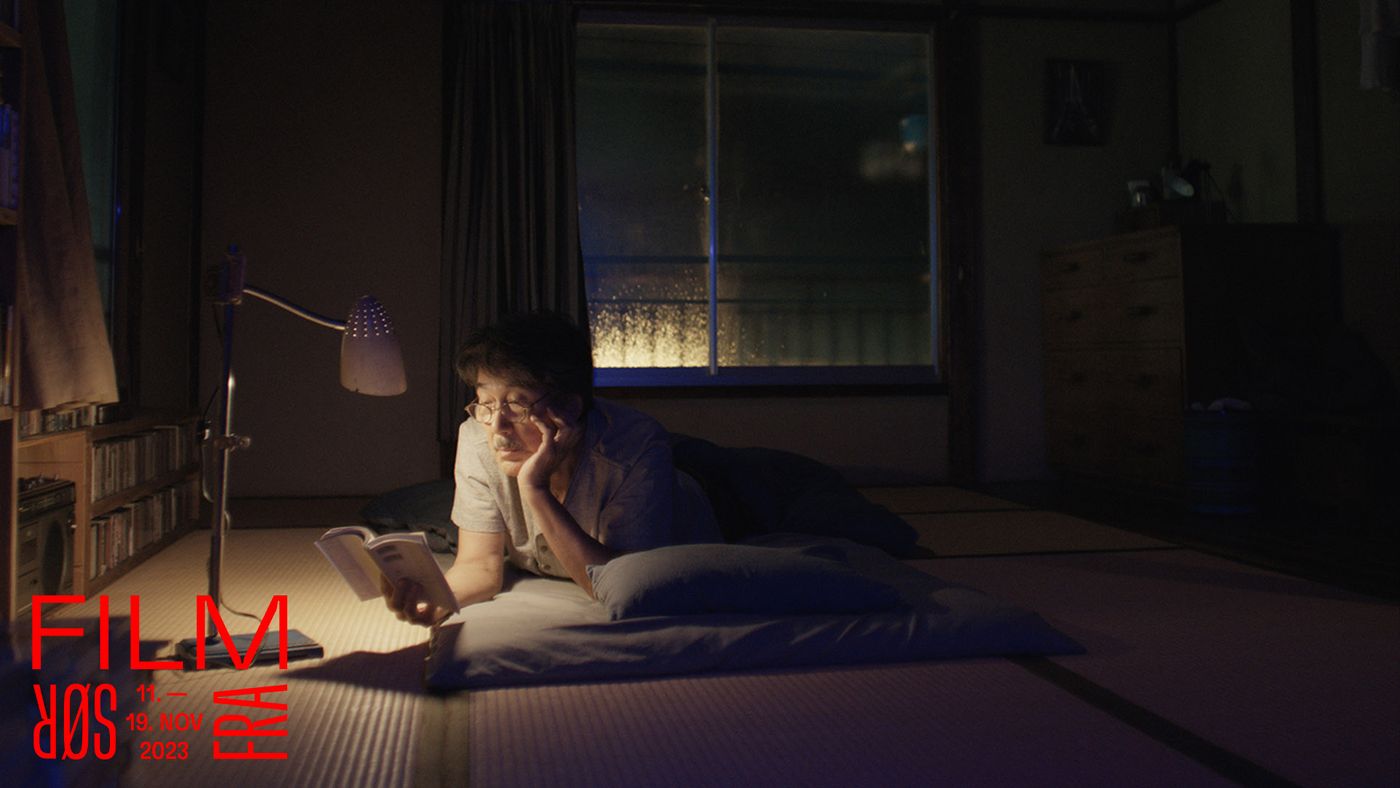 En mann leser en bok under en leselampe