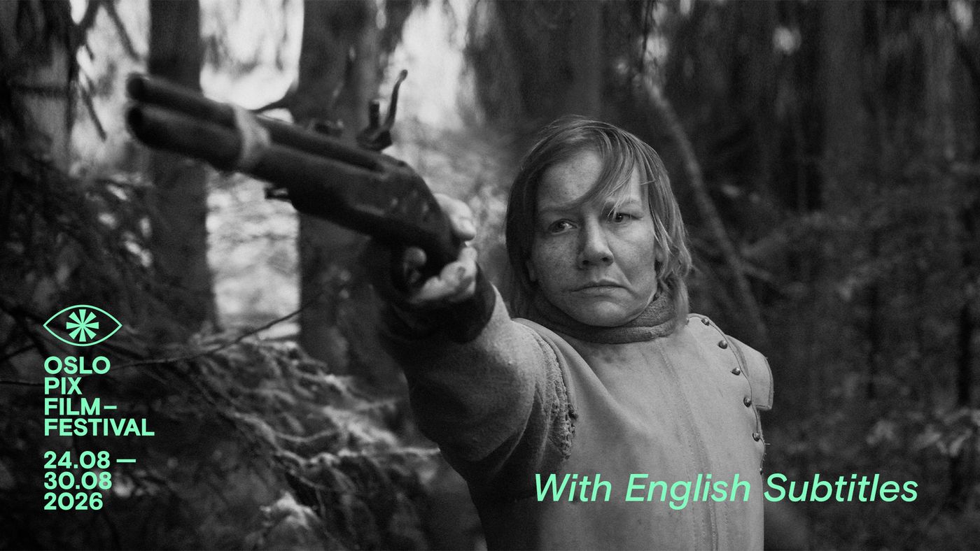 En person står i en skog og peker med en pistol.