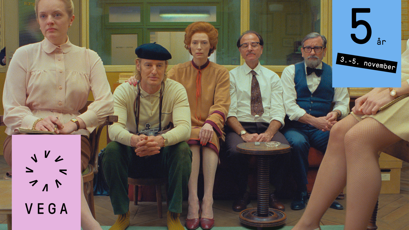 Seks mennesker sitter inne på et kontor i en klassisk Wes Anderson fargepalett