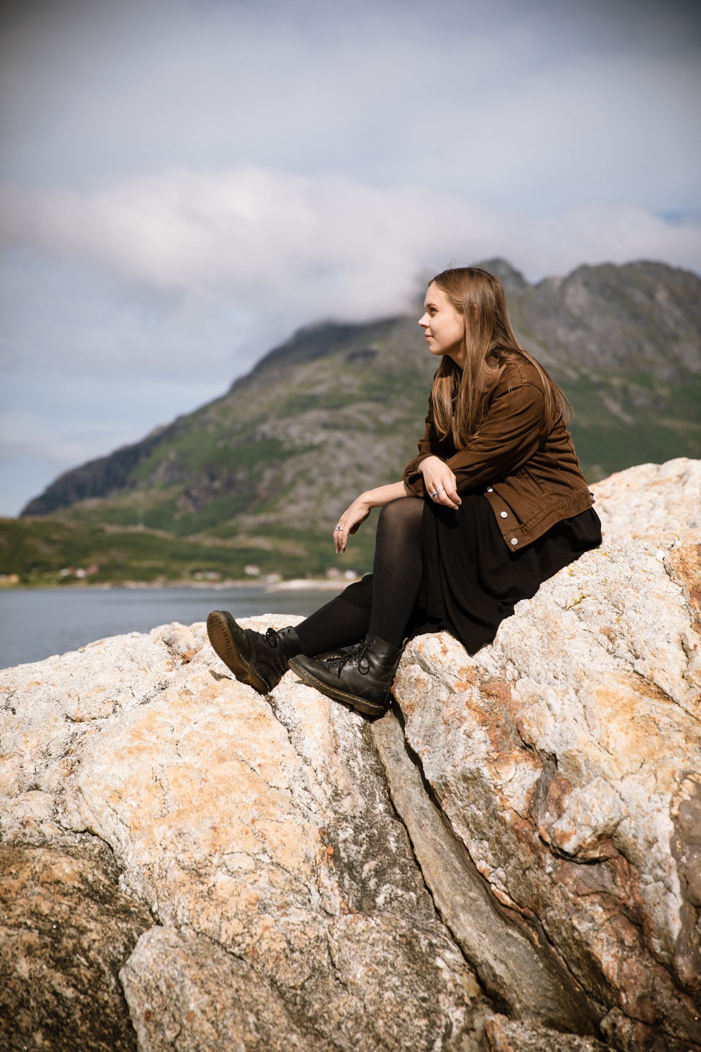 Karoline Una Moen sitter på et berg foran havet.